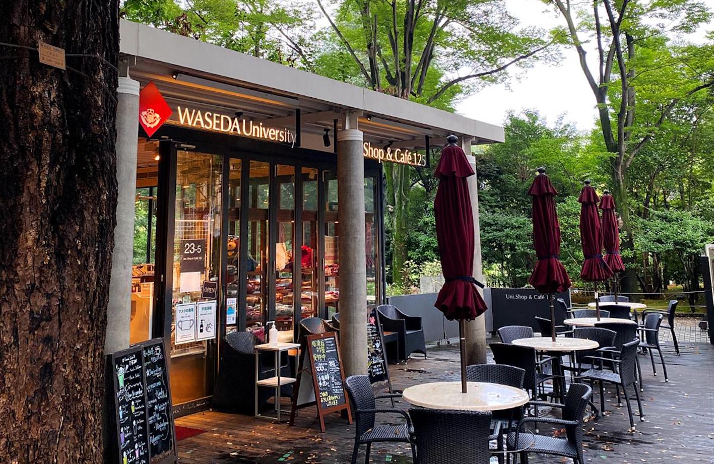 Photo of the Waseda University Uni Shop & Cafe 125. Outdoor seating in the front, trees in the background.